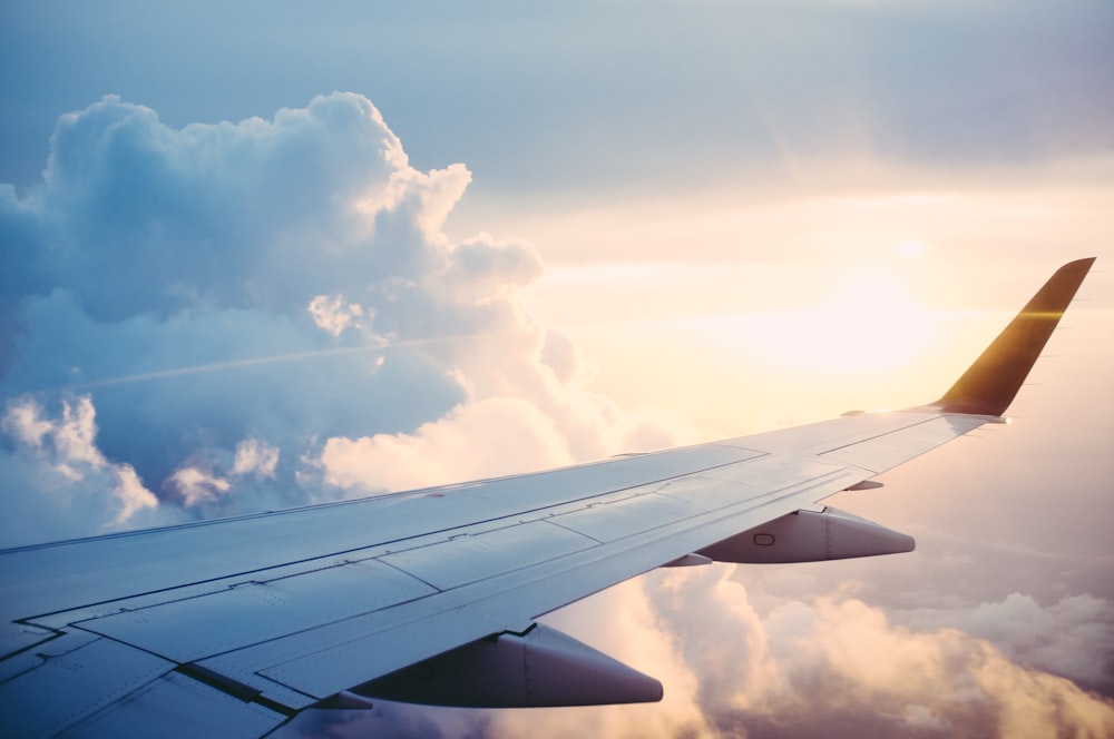 View of an airplane wing above the clouds at sunset